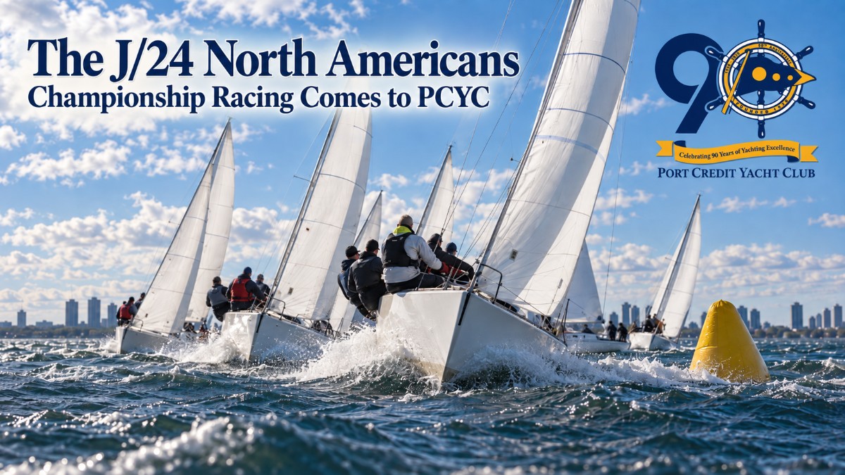 A tight fleet of J/24 keelboats racing upwind on Lake Ontario off Port Credit Yacht Club in autumn, crews hiking out on the rail with the city skyline low on the horizon.